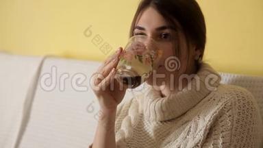 一个年轻的女孩穿着一件舒适温暖的毛衣在<strong>冬天</strong>的晚上在家<strong>喝茶</strong>，想些什么